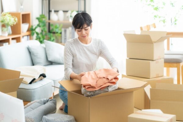 段ボールに洋服を詰める女性