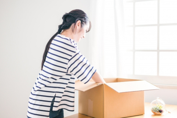 段ボールに荷物を積める女性